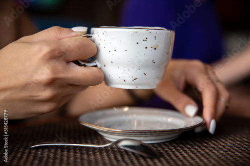 Женские руки с ароматным кофе за столиком в кафе