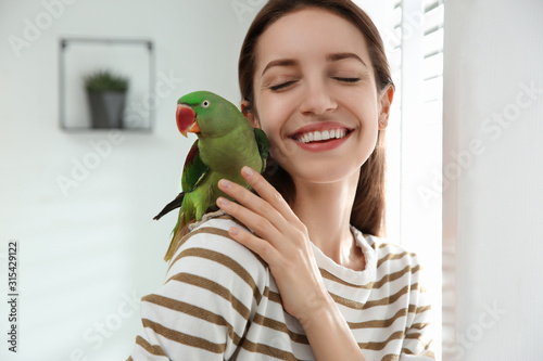 Obraz na płótnie Young woman with cute Alexandrine parakeet indoors