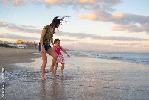 Happy family. Young happy beautiful mother and her daughter having fun on the beach at sunset. Positive human emotions, feelings