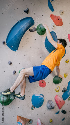 athletischer Mann beim Bouldern an Kletterwand totale Einstellung photo