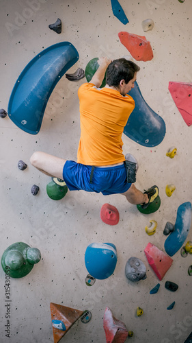 athletischer Mann beim Bouldern an Kletterwand totale Einstellung photo