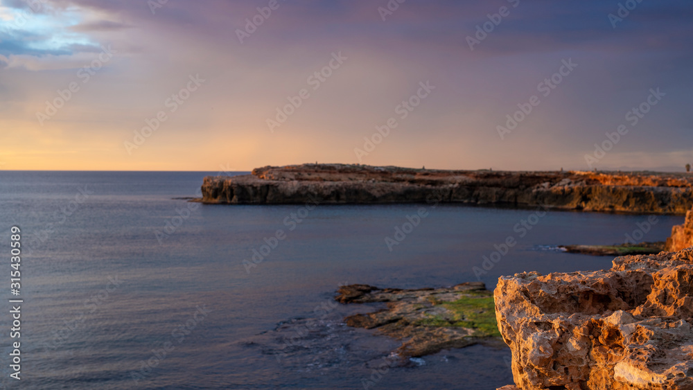Early sunrise and epic cloudy sky at rocky seashore coast of Torrevieja, Alicante, Spain. Mediterranean sea 2019. Selective focus