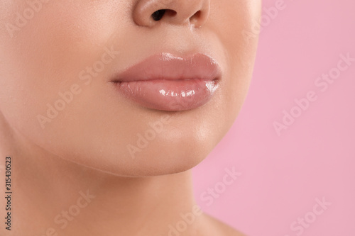 Young woman with beautiful full lips on pink background, closeup