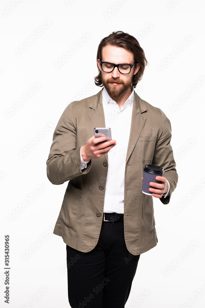 Portrait of a smiling young business man using smartphone and holding cup of coffee isolated on a white background Portrait of a smiling young business man using smartphone and holding cup of coffee isolated on a white background