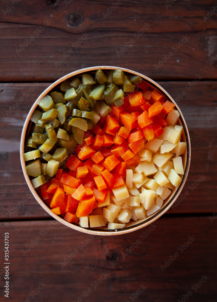 diced vegetables, carrots, potatoes, pickles. Top view on a wooden table. diced vegetables, carrots, potatoes, pickles. Top view on a wooden table.