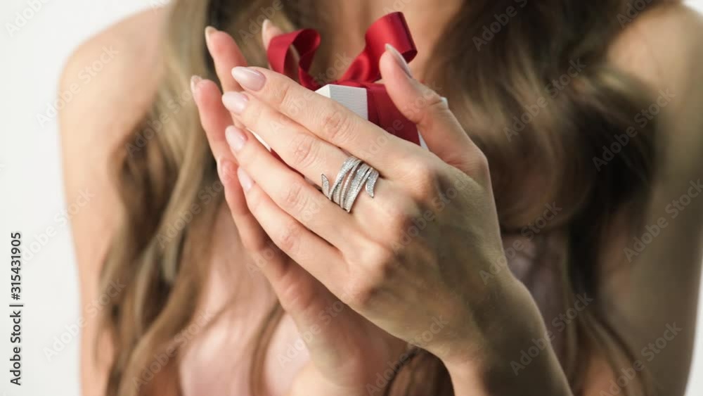 Beautiful woman holding a small gift box with red ribbon. Valentine's Day present Beautiful woman holding a small gift box with red ribbon. Valentine's Day present
