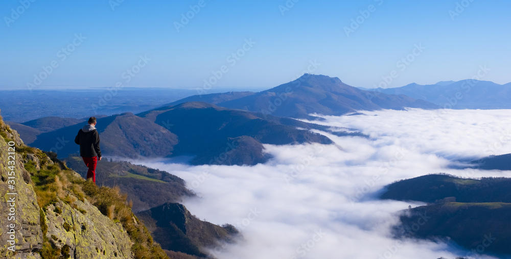 Mountaineer on top of the mountain with sea of clouds in the background, Aiako Harriak Natural Park, Euskadi Mountaineer on top of the mountain with sea of clouds in the background, Aiako Harriak Natural Park, Euskadi