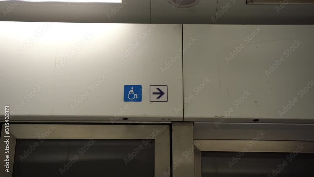 Disabled sign above the doors of public transport with pointing arrow to the entrance or exit. Blue pictogram with man on wheelchair is a handicap symbol. Accessibility for persons with disabilities Disabled sign above the doors of public transport with pointing arrow to the entrance or exit. Blue pictogram with man on wheelchair is a handicap symbol. Accessibility for persons with disabilities