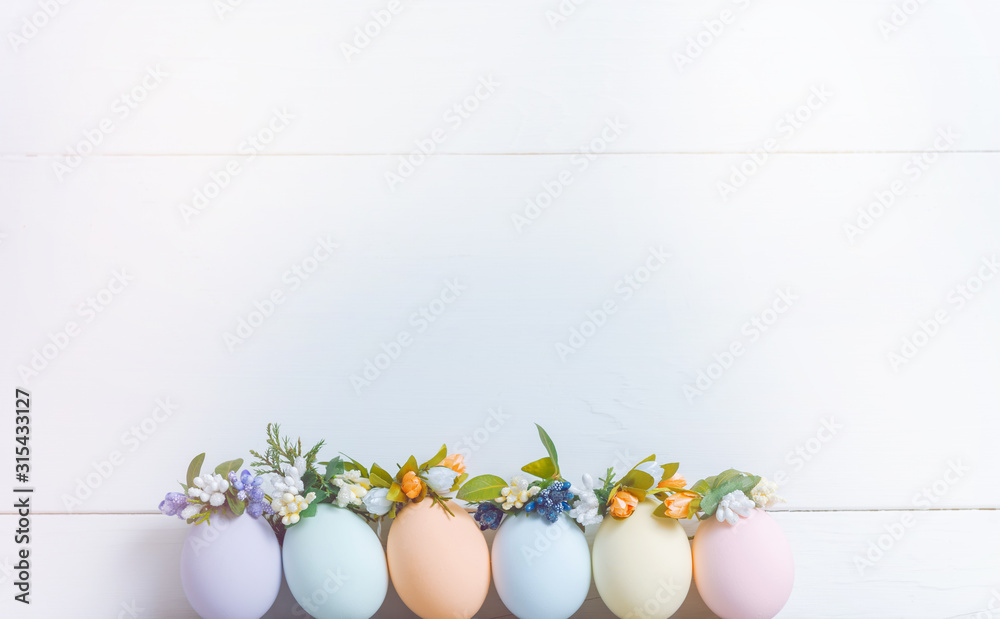 Easter concept. Easter eggs painted in pastel colors in an egg tray with wreaths on them. Light background, place for text. Easter concept. Easter eggs painted in pastel colors in an egg tray with wreaths on them. Light background, place for text.