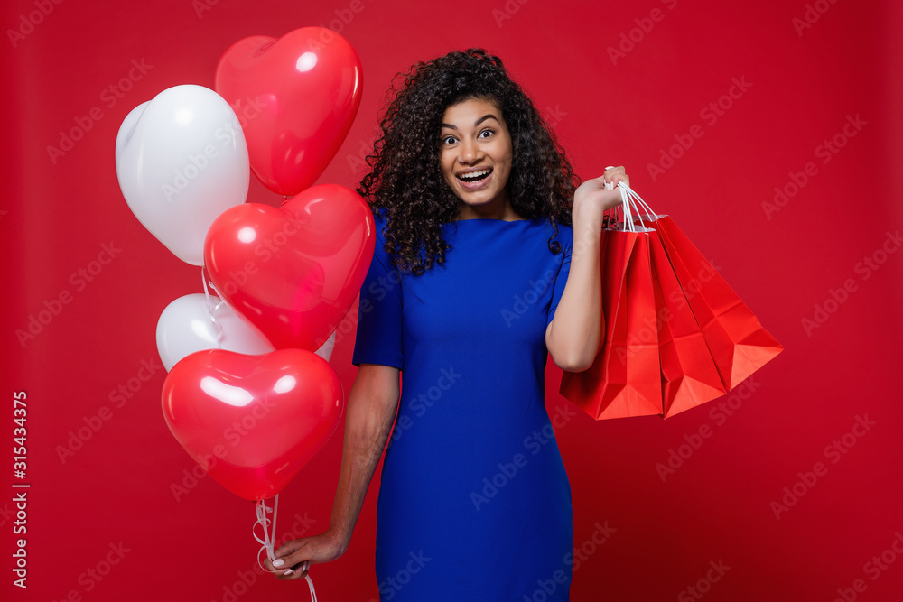 black woman with heart shaped colorful balloons and shopping bags on red background black woman with heart shaped colorful balloons and shopping bags on red background