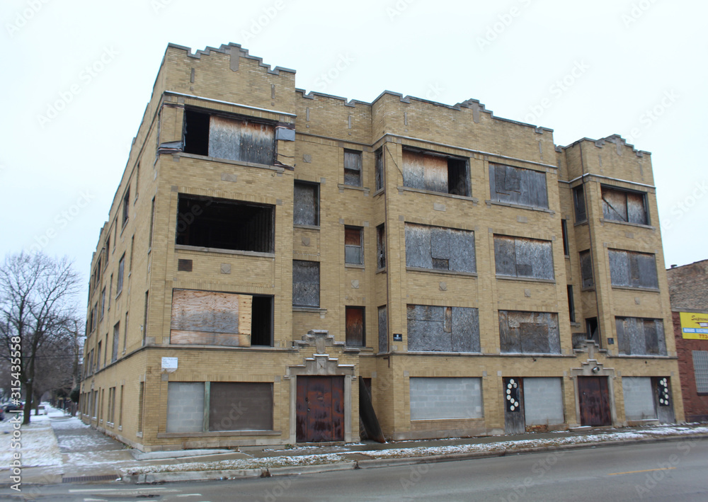 Abandoned and boarded-up yellow brick apartment building in Chicago's Englewood neighborhood in winter