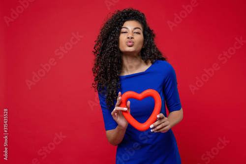 woman giving smooch kiss with heart shape wearing dress on red background