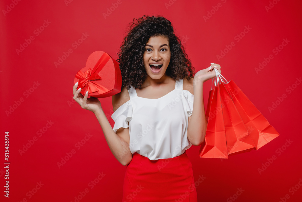 woman with heart shaped gift box and shopping bags on red background woman with heart shaped gift box and shopping bags on red background