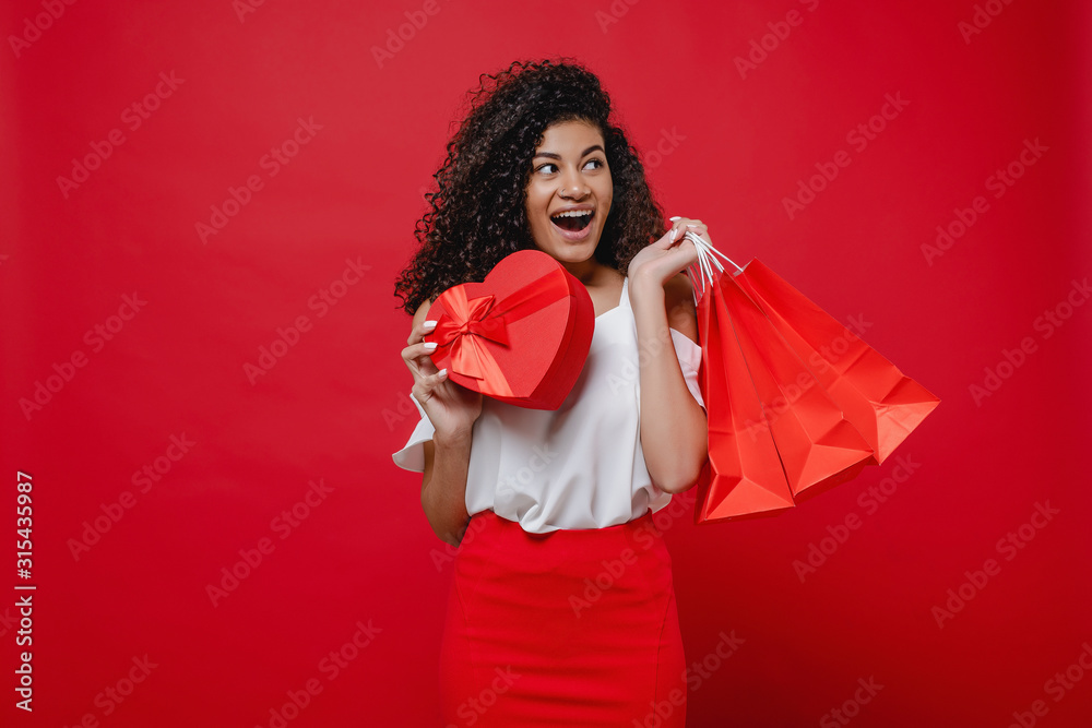 woman with heart shaped gift box and shopping bags on red background woman with heart shaped gift box and shopping bags on red background