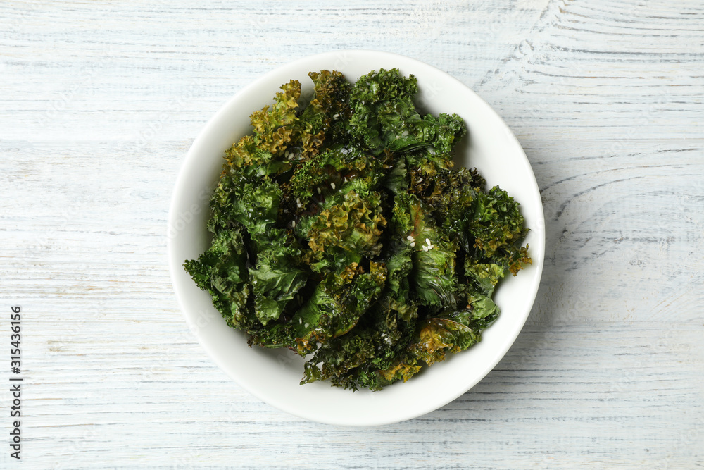 Tasty baked kale chips on white wooden table, top view Tasty baked kale chips on white wooden table, top view