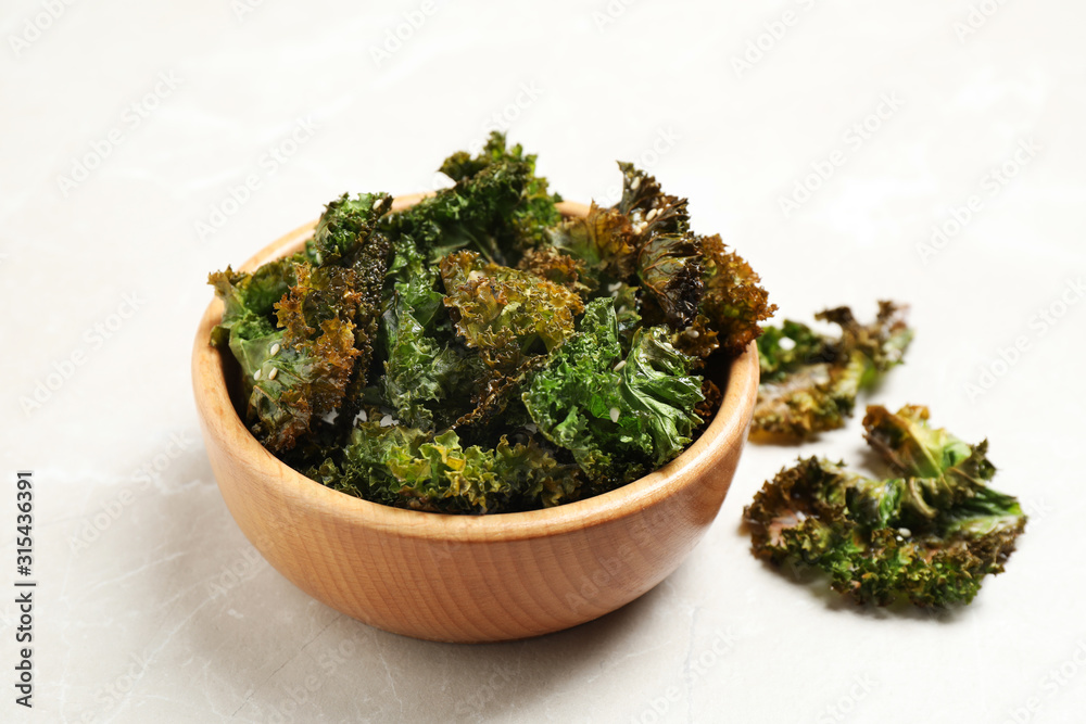 Tasty baked kale chips on grey marble table Tasty baked kale chips on grey marble table