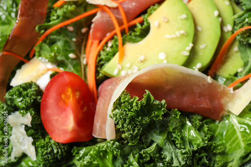 Delicious kale salad with prosciutto as background, closeup