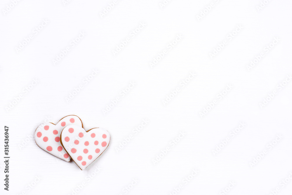 Obraz premium Two gingerbread cookies with frosting in the shape of a heart on white background. Valentines day concept. Flat lay, top view, copy space for text.