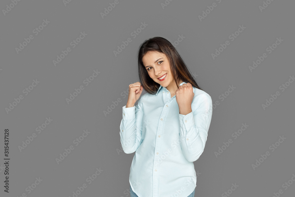 Freestyle. Young woman standing isolated on grey hands in fists successful smiling cheerful Freestyle. Young woman standing isolated on grey hands in fists successful smiling cheerful
