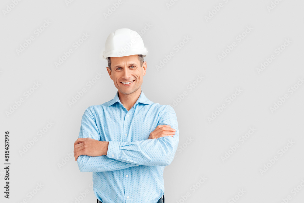 Construction. Mature man in hardhat standing isolated on white crossed arms smiling playful Construction. Mature man in hardhat standing isolated on white crossed arms smiling playful