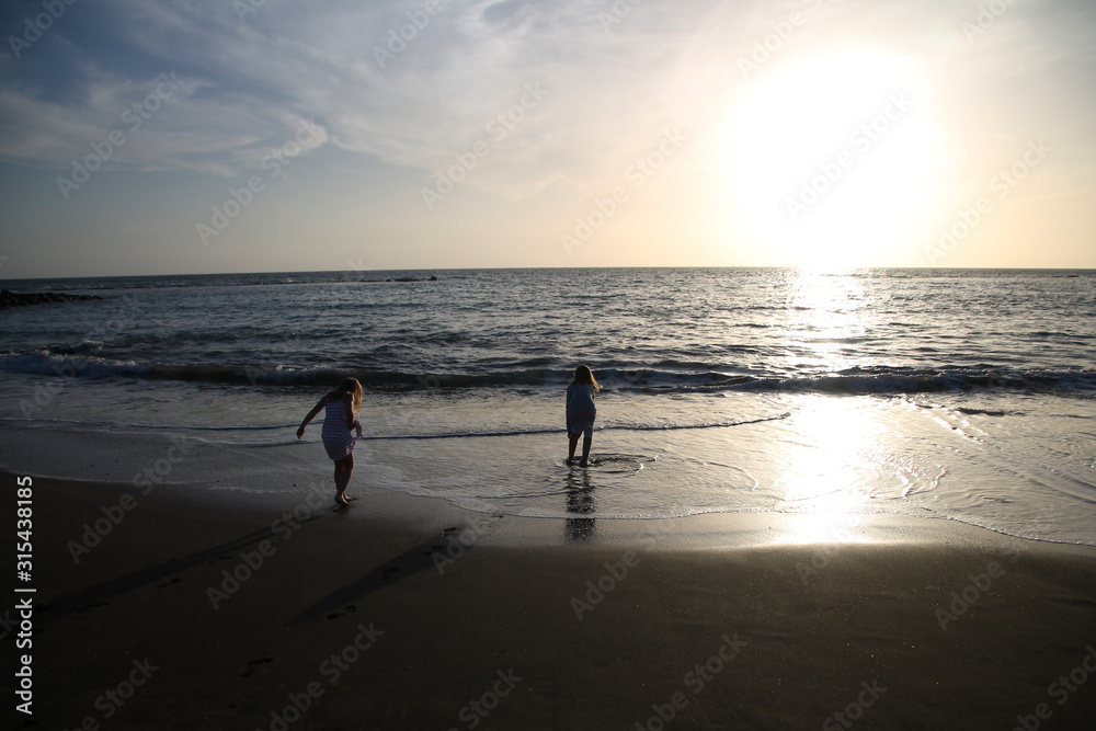 Children playing on the beach in sunset