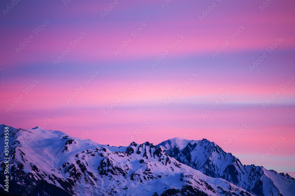 Beautiful sunrise in the mountains, pink clouds in the sky. Winter Alps, France.