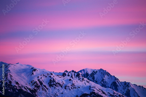 Beautiful sunrise in the mountains, pink clouds in the sky. Winter Alps, France.