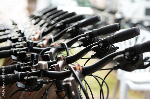 A lot of bikes are behind each other. The upper part of the frame, the steering wheel, and the gearshift are shown. Selective focus. Defocused image.