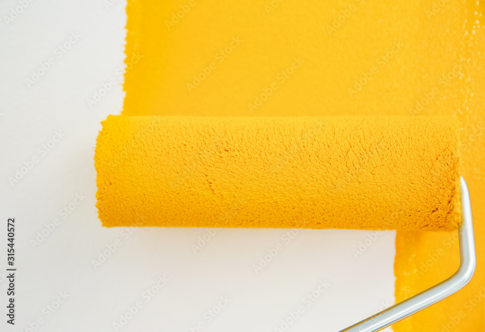 Obraz premium Painting white wall with yellow dye, closeup. Interior renovation