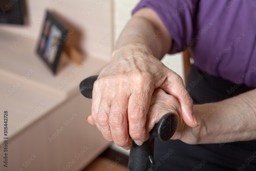 Hands of an elderly woman on the handle of a cane