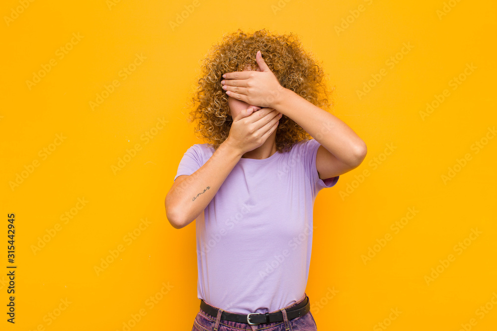 young afro woman covering face with both hands saying no to the camera ...