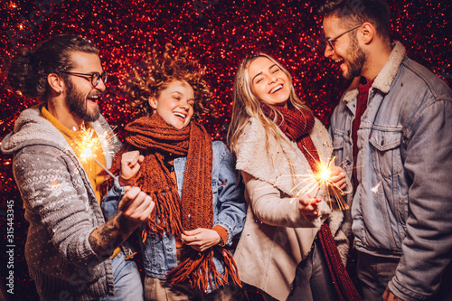 Group of happy friends celebrating New Year with sparklers. New year party.