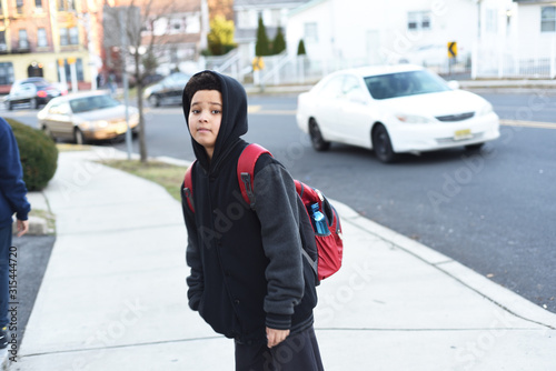 Portrait of the cute african american boy who is going to school with his school backpack. Student mixed boy on his way to the school. Study for children. Road. Shooting on the july 2018. 