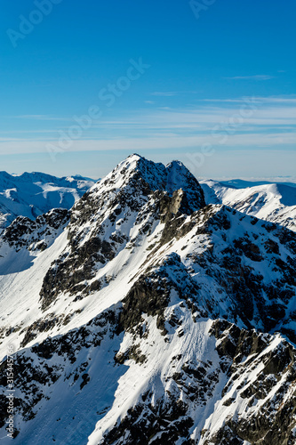 View of the outstanding peak in the High Tatras located on the Polish-Slovak border - Swinica (Svinica ). Tourists and mountaineers visible on the tops. Winter landscape.