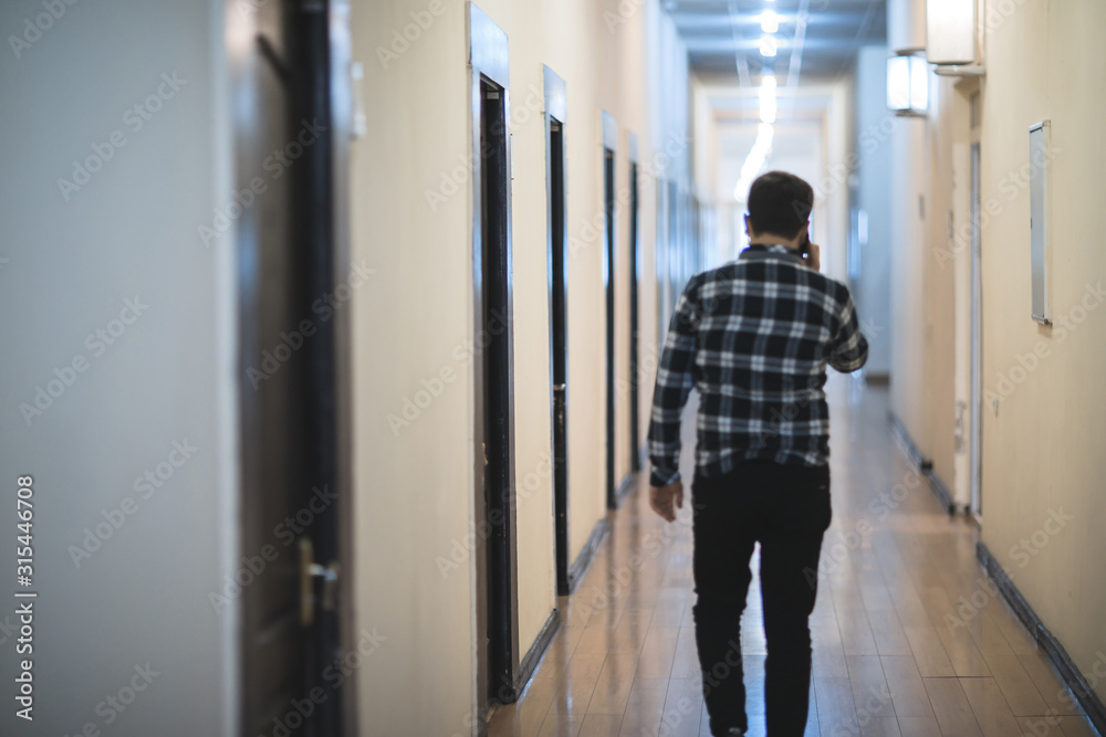 man walking in the corridor hand phone