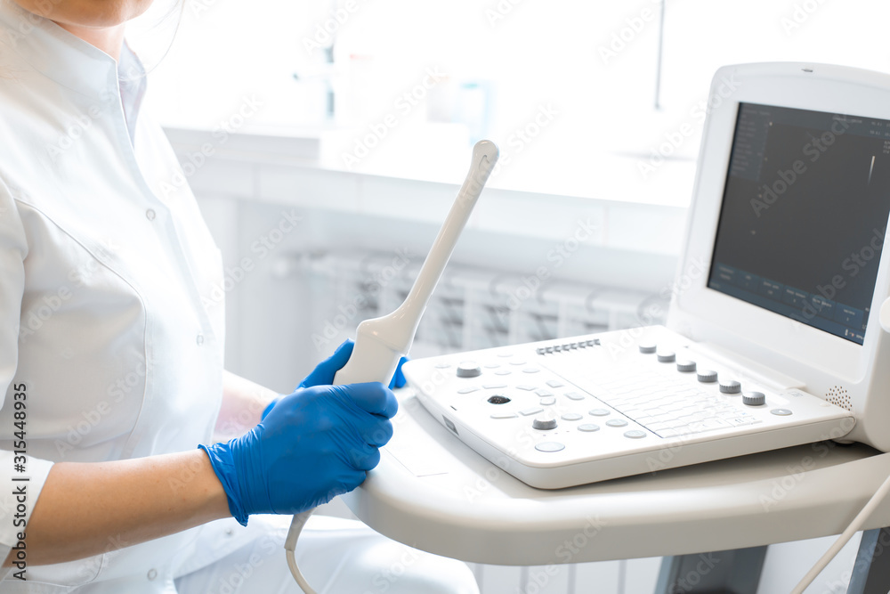 A gynecologist sets up an ultrasound machine. A transvaginal ultrasound scanner of the internal organs of the pelvis. Female health concept A gynecologist sets up an ultrasound machine. A transvaginal ultrasound scanner of the internal organs of the pelvis. Female health concept