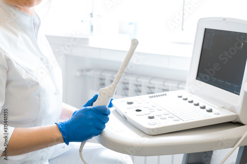 A gynecologist sets up an ultrasound machine. A transvaginal ultrasound scanner of the internal organs of the pelvis. Female health concept