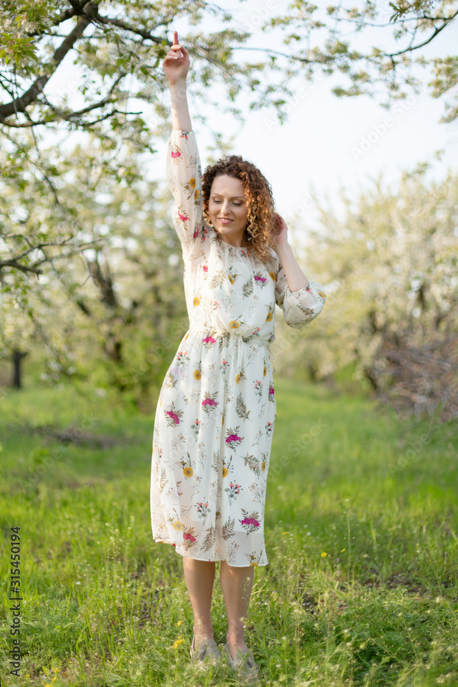 Young attractive girl walks in spring green park enjoying flowering nature Young attractive girl walks in spring green park enjoying flowering nature
