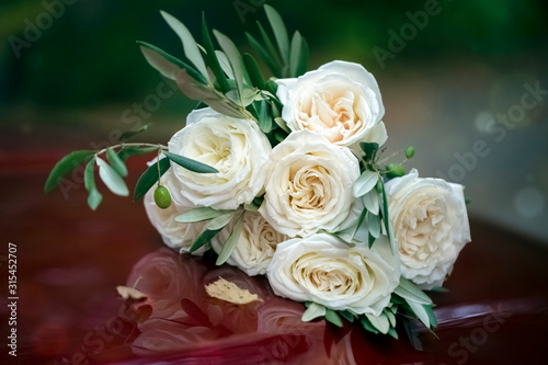 Beautiful wedding bouquet of white roses on a red hood of a car. Close-up. Background  texture. Tinting