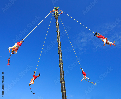 The Voladores, or flyers performance. They climb up a very high pole their waist to ropes wound around the pole and then jump off, flying gracefully around it.