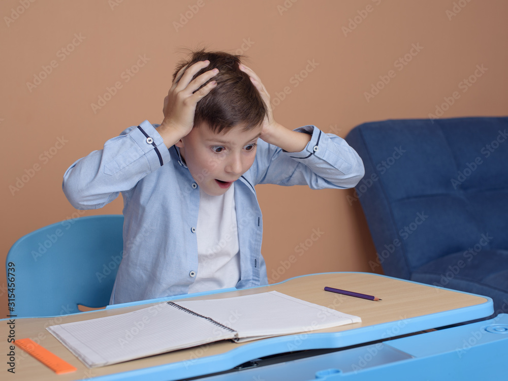 Emotional European schoolboy going crazy of difficult task while doing his home assignment. Emotional European schoolboy going crazy of difficult task while doing his home assignment.