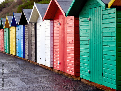 Row of individual beach huts in primary colours on Lowestoft sea front.