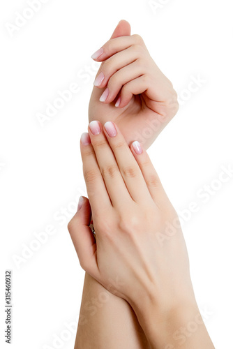 closeup of hands of a young woman with long pink manicure on nails against white background