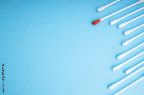 Blood on the hygiene cotton stick. Skincare mockup for design. Menstruation. Stack of disposable cotton stick on a blue background. Cosmetology concept. Bloody wound. Injury. ..