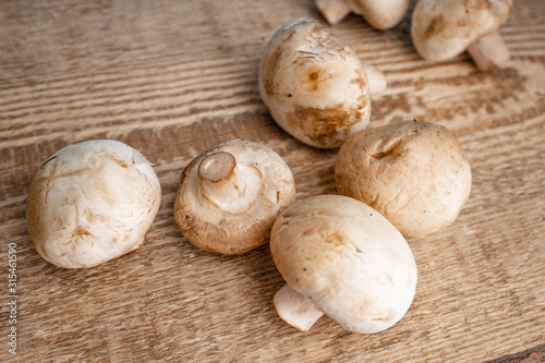Bunch of fresh champignon mushrooms on the wooden background. Close up of vegetarian healthy food.