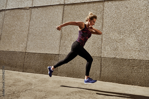 Woman running on the city street against modern city walls