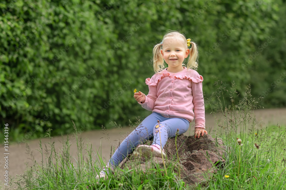 Little girl sitting on the stone and laughs Little girl sitting on the stone and laughs