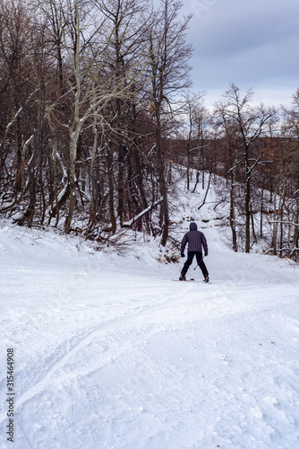 A man on a cloudy winter day is skiing down the mountainside.