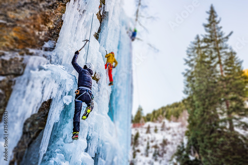 Ice Climbing Man with an Ice Axe and Crampons on a Frozen Waterfall