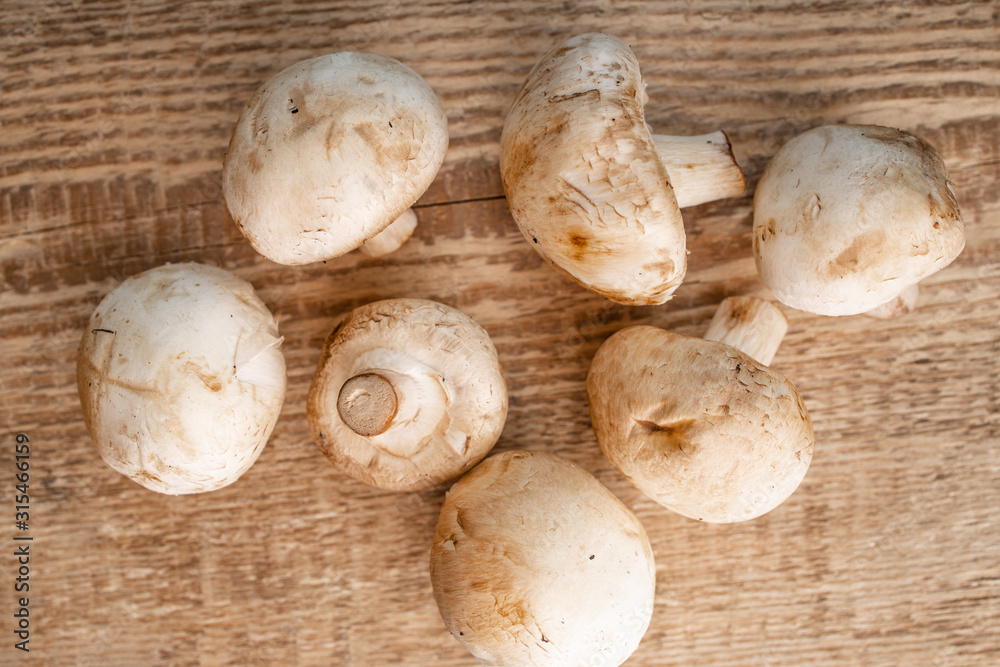 Bunch of fresh champignon mushrooms on the wooden background. Close up of vegetarian healthy food.